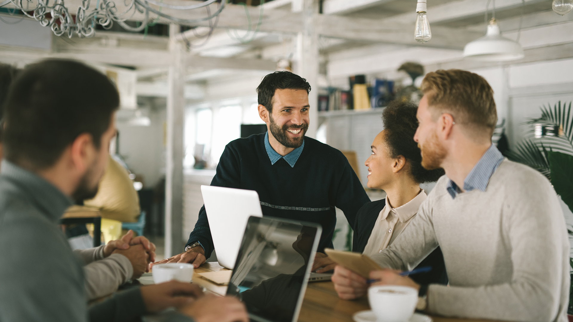 Business people meeting in open workspace and using laptops